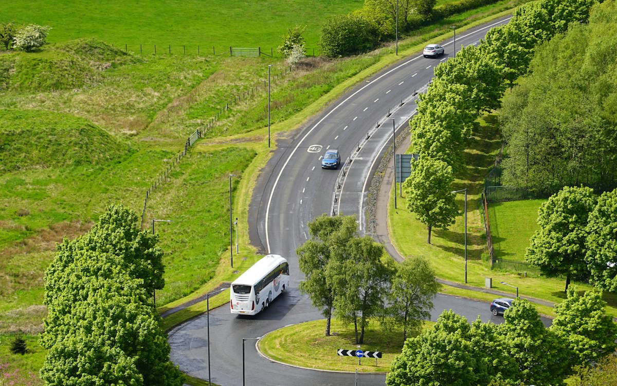 Ônibus de viagem em uma estrada cercada de verde